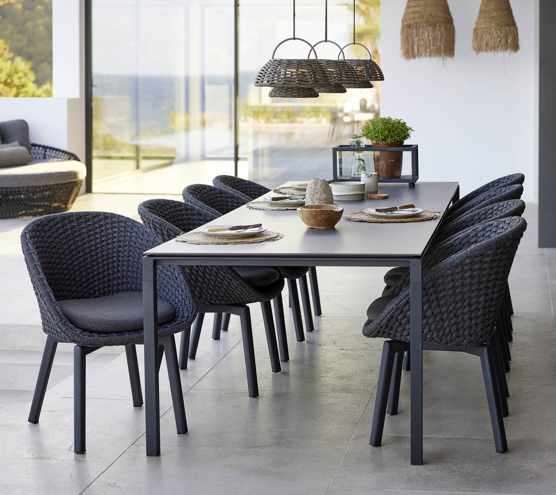 Een stijlvolle eetopstelling met een puur eettafel, pauwenstoelen en een illusielamp, die een moderne esthetiek versterkt.
