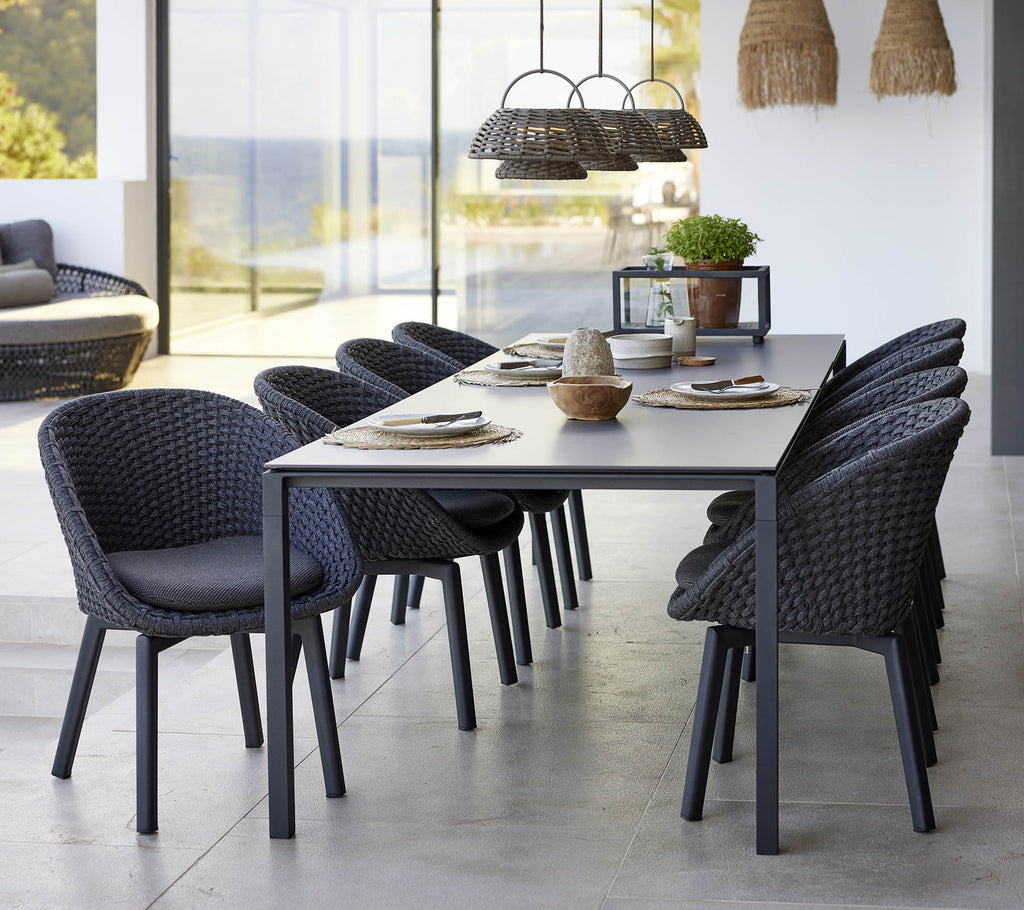 Een stijlvolle eetopstelling met een puur eettafel, pauwenstoelen en een illusielamp, die een moderne esthetiek versterkt.