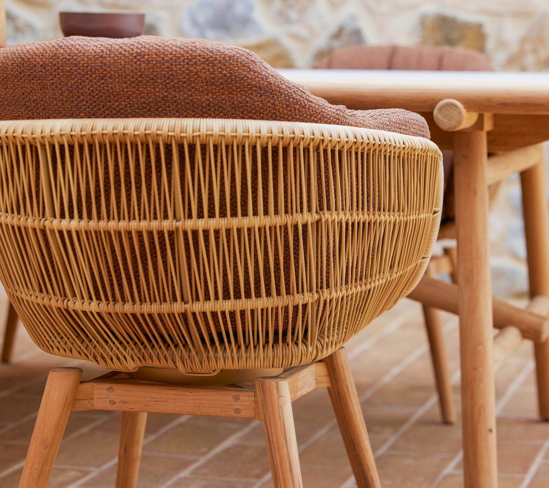 Draaiende eetstoel met een geweven ontwerp en teakhouten poten, voorzien van een comfortabele Rice-kussen voor extra stijl en comfort.
