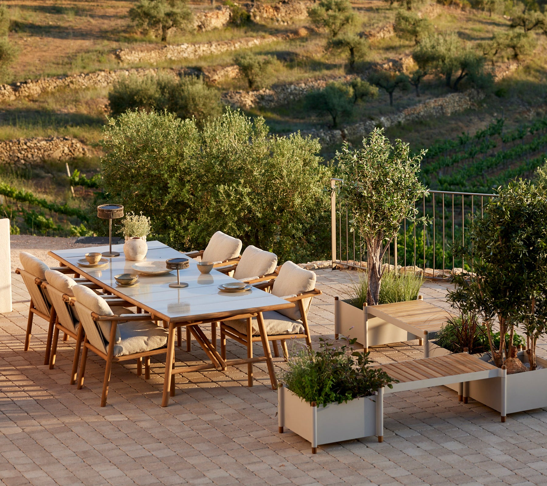 Een stijlvol eetsysteem met teakaccenten, met comfortabele stoelen en een plantenbank, omgeven door groen.