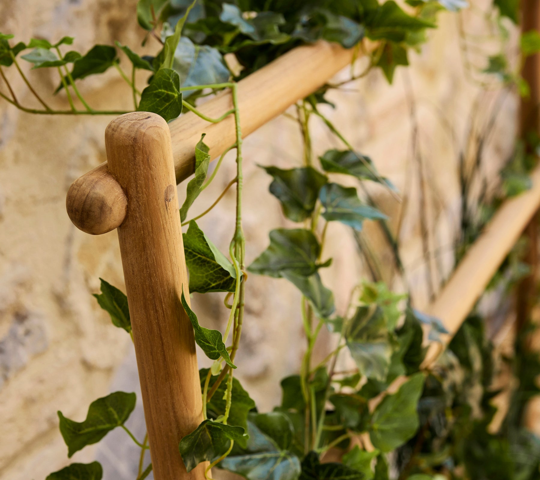 Een houten stokpot met weelderige groene wijnstokken die naar beneden vallen en een natuurlijk accent aan de presentatie toevoegen.