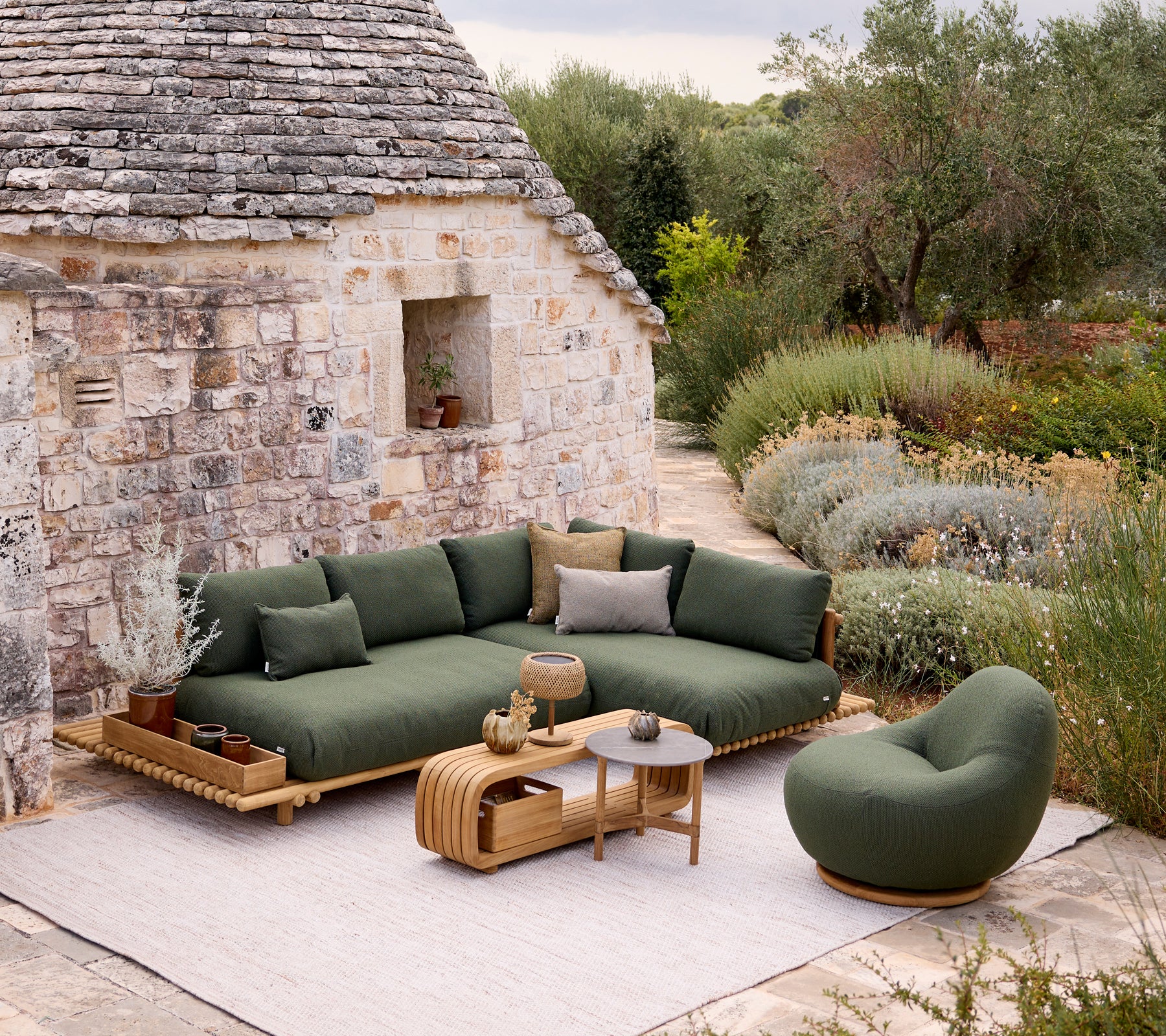 Moderne groene bank en stoel met een bruine tafel in een tuinsetting.