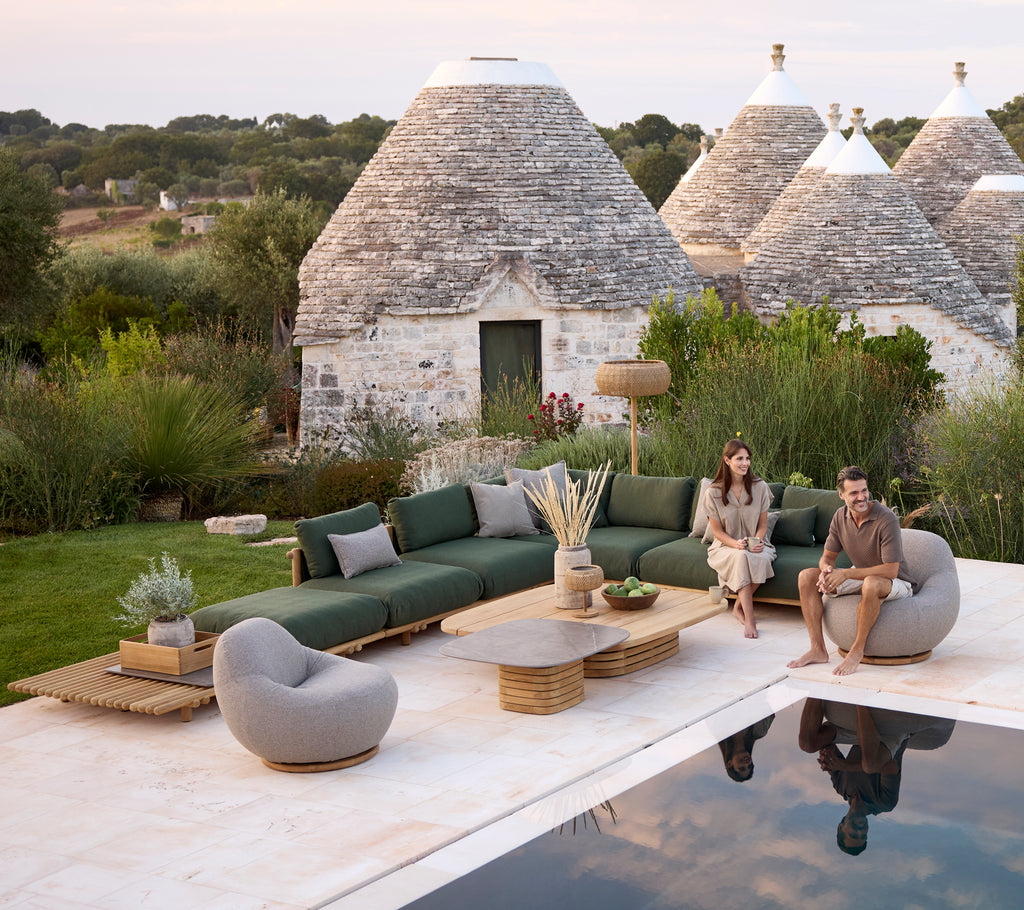 Moderne buiten loungegebied met een groene bank, een grijze stoel en een ronde salontafel.