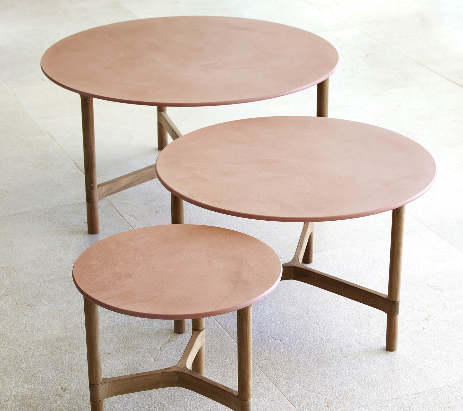 Drie ronde salontafels in verschillende maten, met een minimalistisch ontwerp met houten benen en een glad, elegant oppervlak.