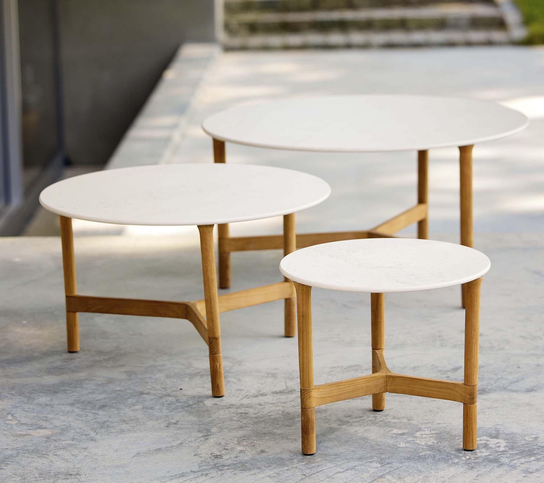 Drie moderne salontafels in verschillende maten met witte tops en houten benen, met een stijlvolle en minimalistische uitstraling.