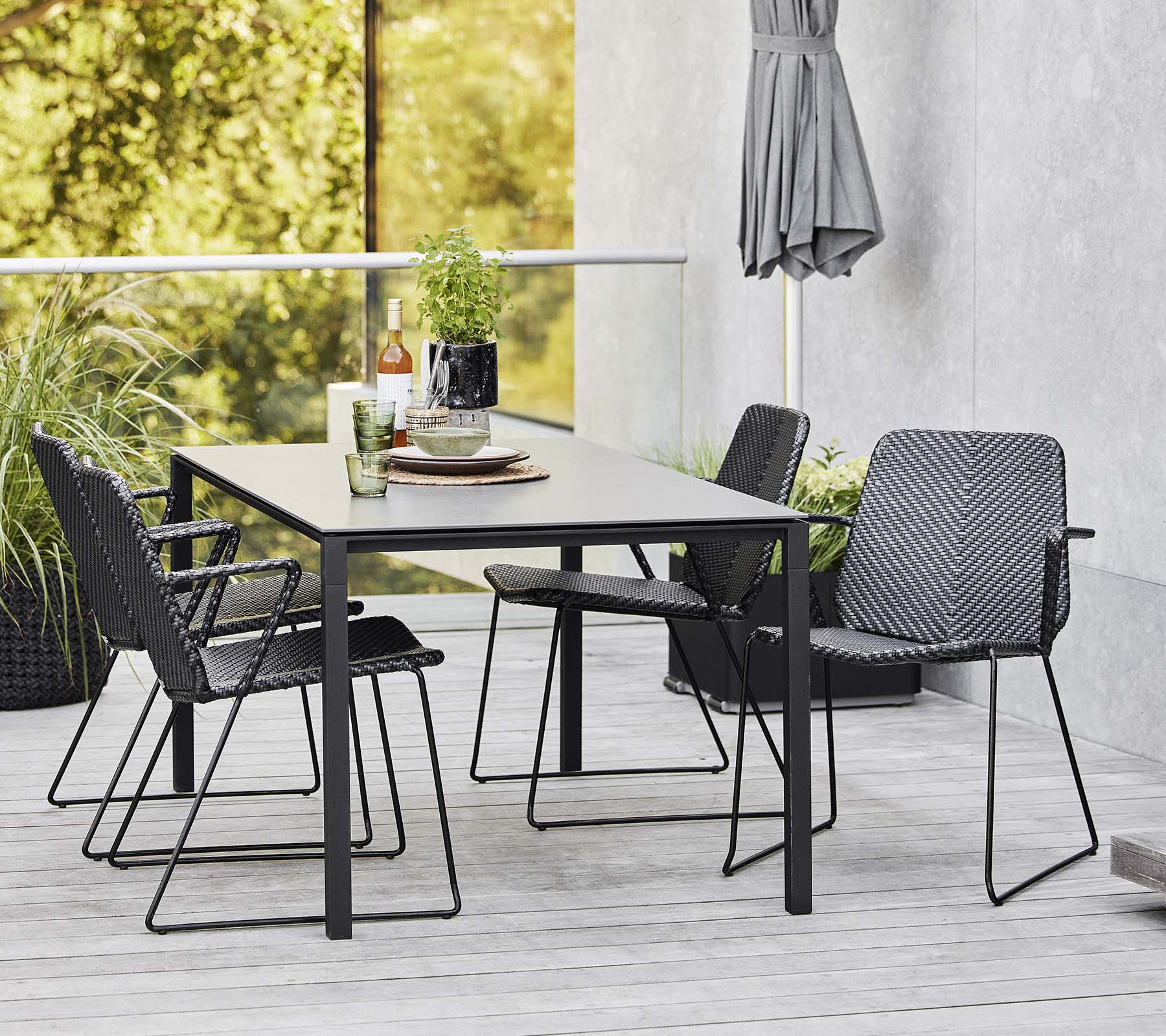 Een moderne tafel omringd door stijlvolle stoelen, aangevuld met decoratieve items en groen op de achtergrond.
