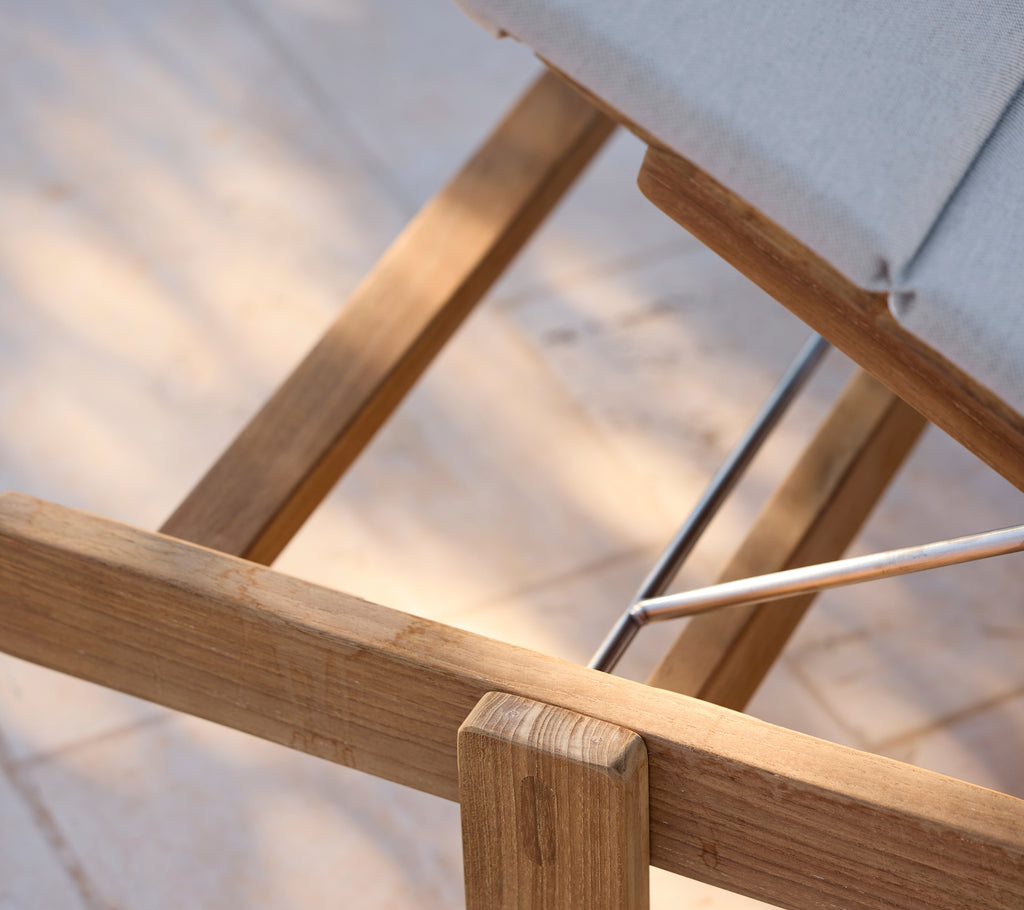 Moderne loungestoel met een grijze kussen en houten frame.