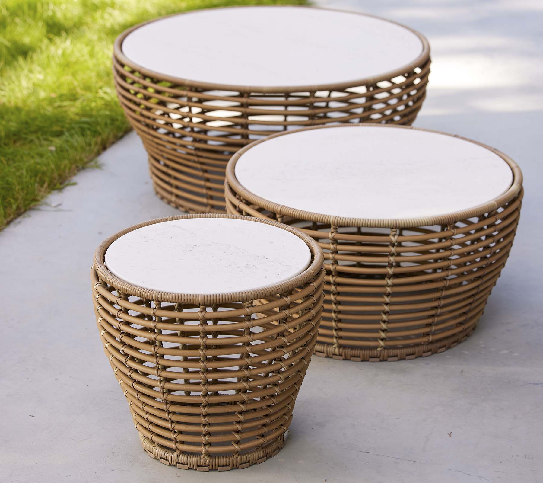 Drie gevlochten mand koffie tafels in verschillende maten, met ronde witte tops en een natuurlijk ontwerp, ideaal voor een stijlvolle woonkamer.