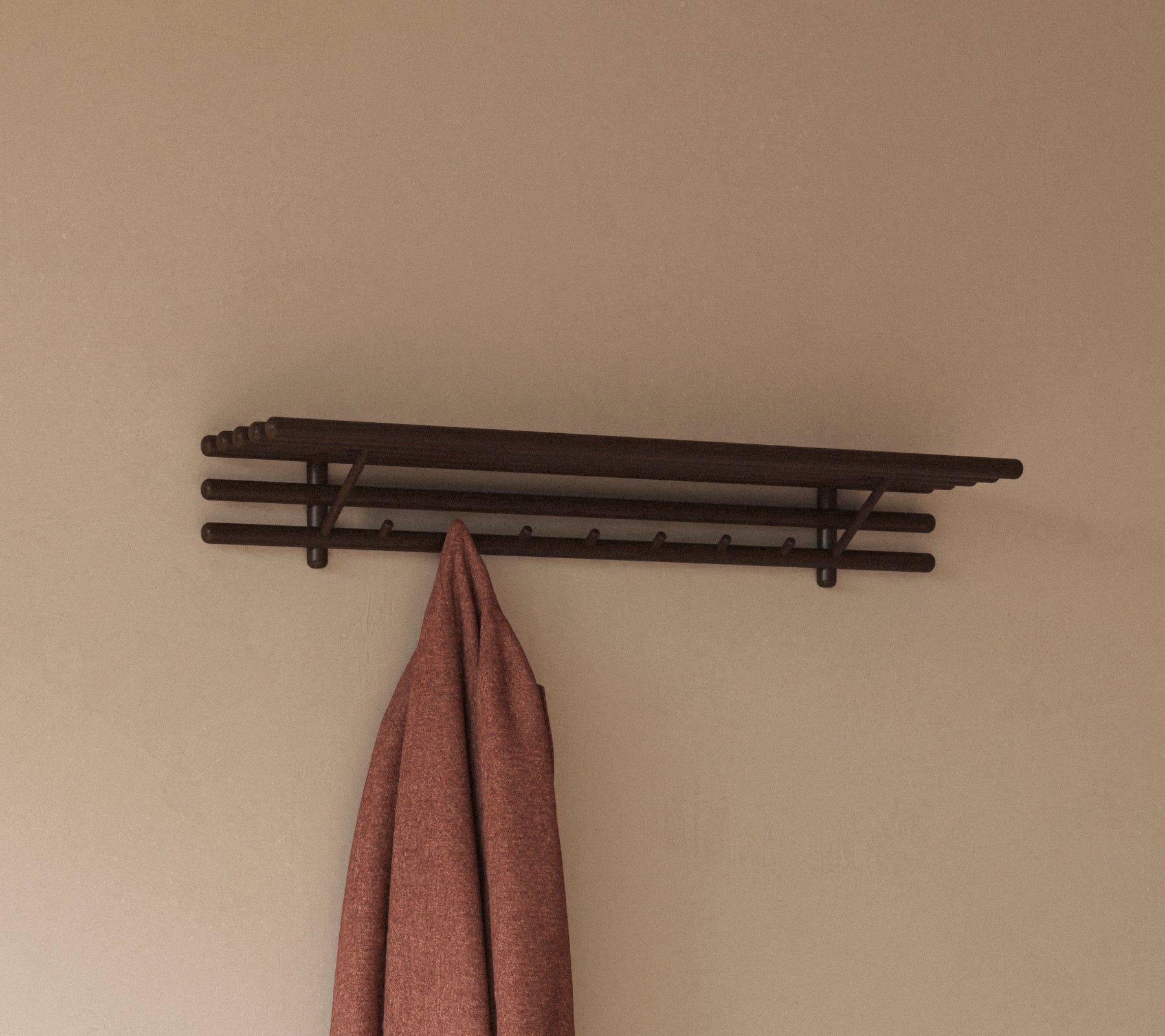 Een minimalistisch plank met meerdere haken die een hangdoek vasthouden, ontworpen voor praktische opslag en organisatie.