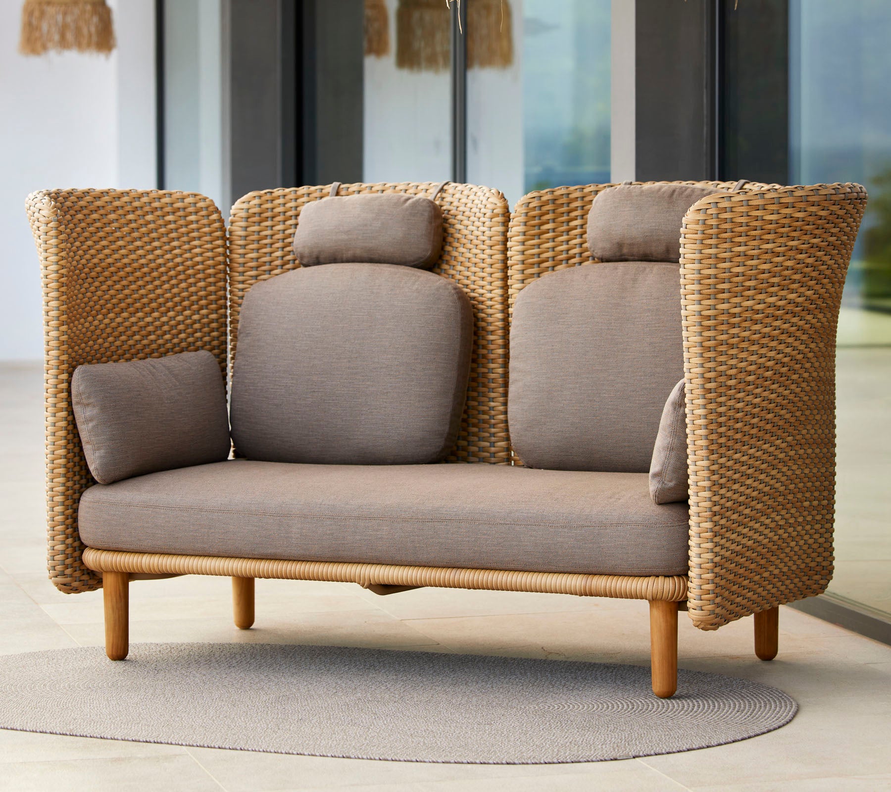 Stijlvolle tweezits bank met geweven textuur, met comfortabele kussens en een basis van natuurlijk hout, ideaal voor ontspanning.