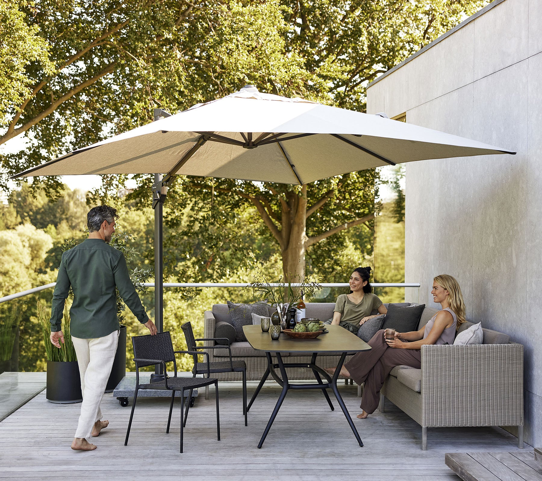 Een stijlvol zitgedeelte met een grote parasol, met een bank, stoelen en een eettafel omringd door weelderig groen.